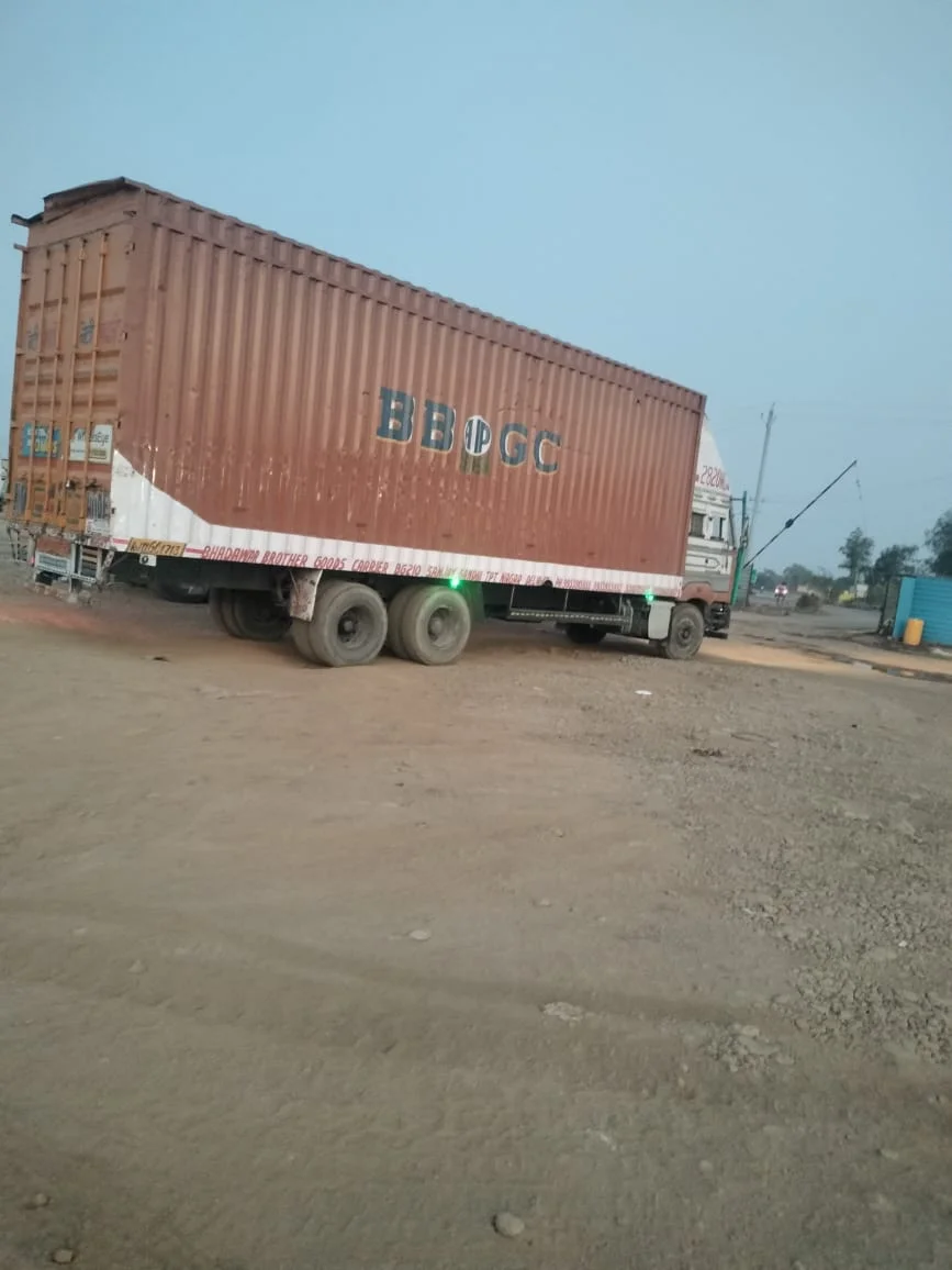 32 Ft Truck Booking in Pune | SXL & MXL 2 Long brown container-body goods truck parked on an unpaved transport yard