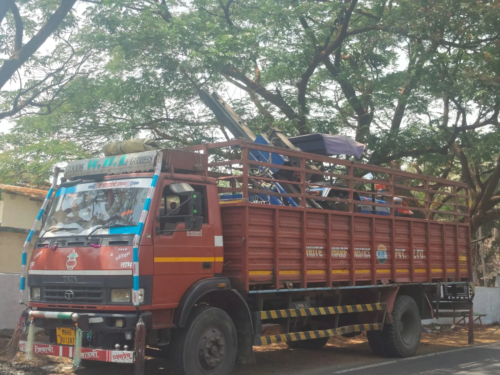 Red open-body goods truck carrying machinery and industrial equipment